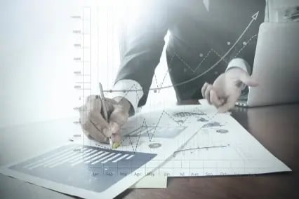 Close up of a man marking documents on a table with charts Close up of a man marking documents on a table with charts